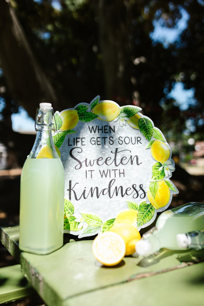 Refreshing lemonade with a motivational sign under natural light outdoors.